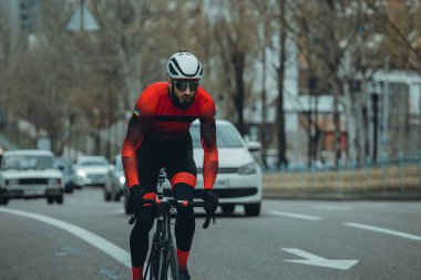 Şehirde bisiklete binen genç adam, gündüz manzaralı. 