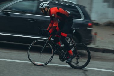 Şehirde bisiklete binen genç adam, gündüz manzaralı. 