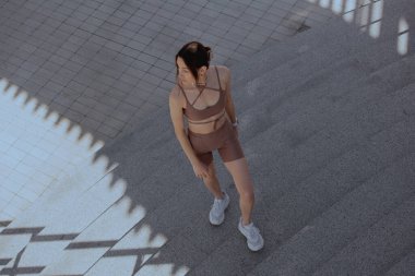 Genç bir kadın şehrin ortasında dışarıda egzersiz yapıyor.