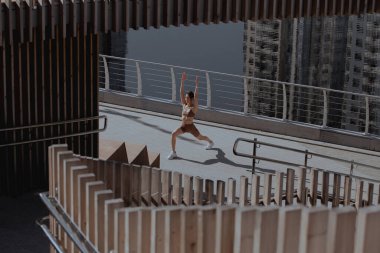 Genç bir kadın şehrin ortasında dışarıda egzersiz yapıyor.