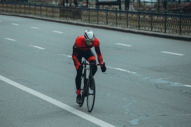 Şehirde bisiklete binen genç adam, gündüz manzaralı. 