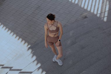 Genç bir kadın şehrin ortasında dışarıda egzersiz yapıyor.