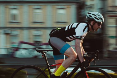 Şehirde bisiklete binen genç adam, gündüz manzaralı. 