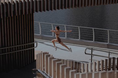 Genç bir kadın şehrin ortasında dışarıda egzersiz yapıyor.