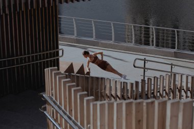 Genç bir kadın şehrin ortasında dışarıda egzersiz yapıyor.