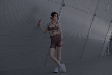 Genç bir kadın şehrin ortasında dışarıda egzersiz yapıyor.