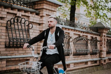 Şehirde bisiklete binen genç adam, gündüz manzaralı. 