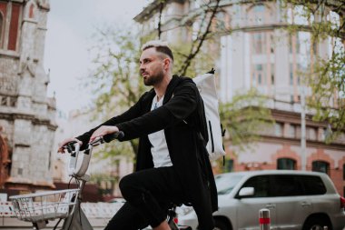 Şehirde bisiklete binen genç adam, gündüz manzaralı. 