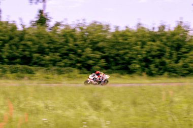 Bir motosiklet yarışçısı motosiklet pistinde hızlı sürüyor..