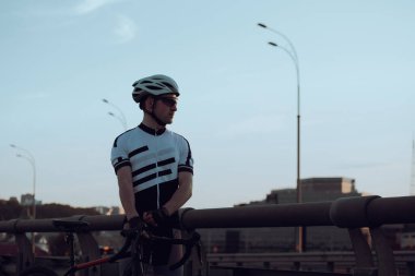 Şehirde bisiklete binen genç adam, gündüz manzaralı. 