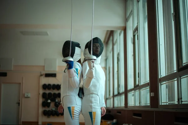 Fencing sport. Two girl fencers training in hall.