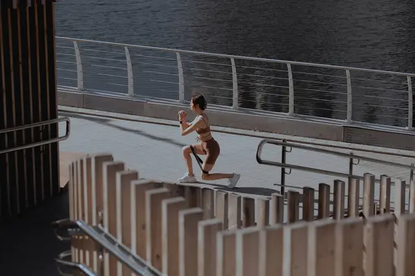 Genç bir kadın şehrin ortasında dışarıda egzersiz yapıyor.