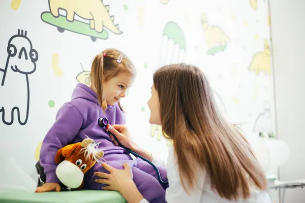 Çocuk doktoru klinikteki kızı kontrol ediyor.