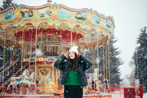 白冬の若いブルネット女性ハットウォーキング雪の公園 — ストック写真