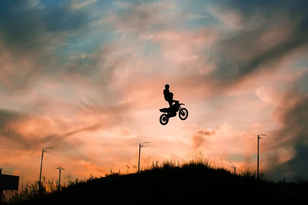 FMX rider performs dangerous stunts at sunset
