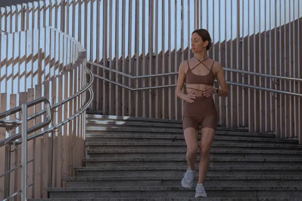 Genç bir kadın şehrin ortasında dışarıda egzersiz yapıyor.