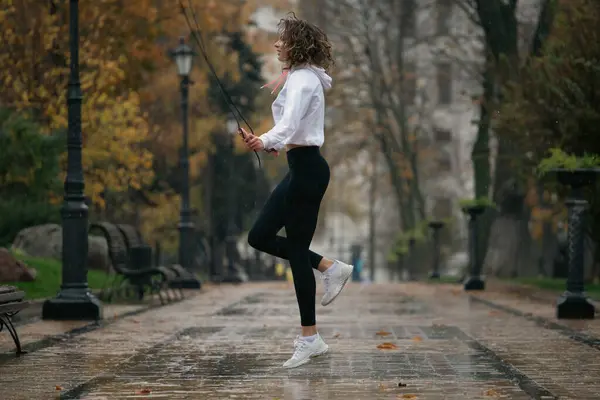 雨の公園で訓練する若い女性 屋外で運動する女性のジョギング — ストック写真