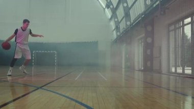 Genç oyuncu sahada basketbol oynuyor.