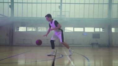 Genç oyuncu sahada basketbol oynuyor.