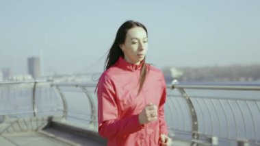 Genç bir kadın dışarıda antrenman yapıyor. Sportif kız şehirde koşuyor.