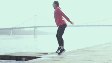 Nehir kıyısında egzersiz yapan genç bir kadın. Şehirde sportif bir kız