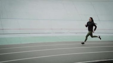 Atletik kız stadyumda koşuyor ve antrenman yapıyor..