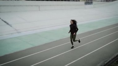 Atletik kız stadyumda koşuyor ve antrenman yapıyor..