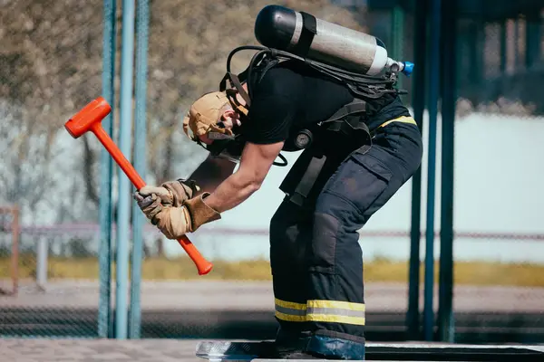 Feuerwehrmann Mit Sauerstoffballon Und Hammertraining Auf Dem Sportplatz — Stockfoto