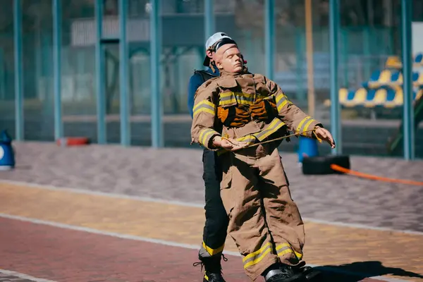 Mutiger Feuerwehrmann Bei Maskentraining Mit Attrappe Auf Dem Sportplatz Stockbild