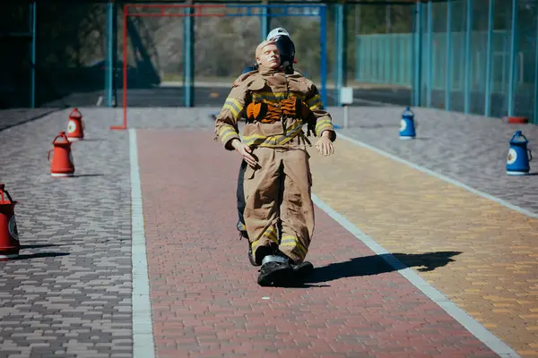 Pompier Courageux Dans Formation Masque Avec Mannequin Sur Terrain Sport Photo De Stock