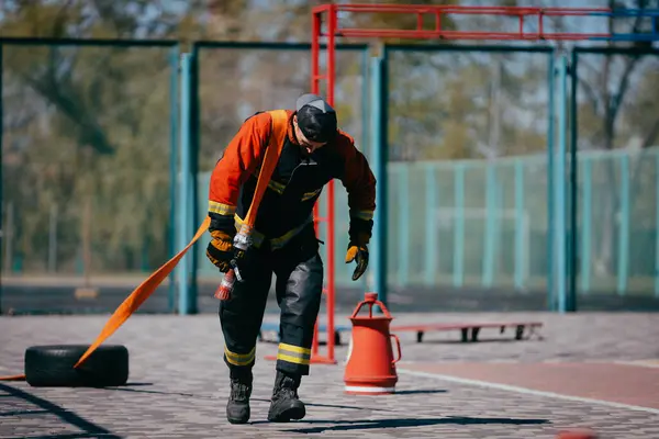 Mutiger Feuerwehrmann Übt Mit Schlauch Auf Dem Sportplatz Stockbild