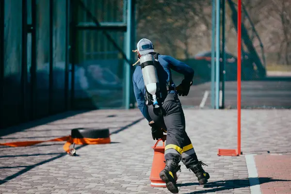 用氧气筒在运动场上进行消防员训练 免版税图库照片