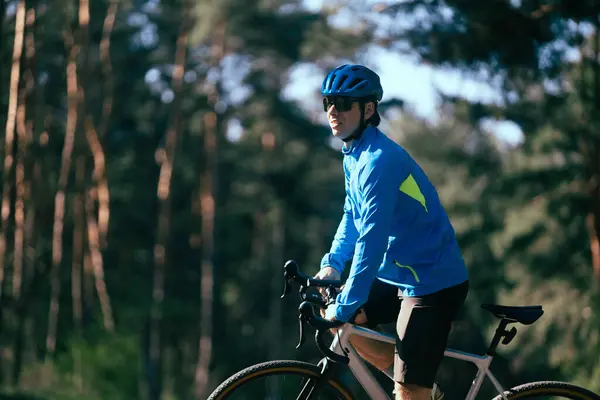 森の道路で自転車で若い男性サイクリスト ロイヤリティフリーのストック写真