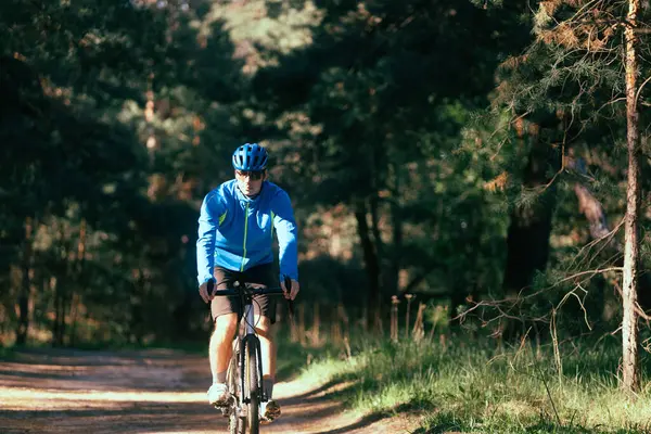 在森林里骑山地自行车的年轻人 图库照片