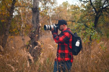 Kameralı fotoğrafçı ve arka planda sonbahar manzarası