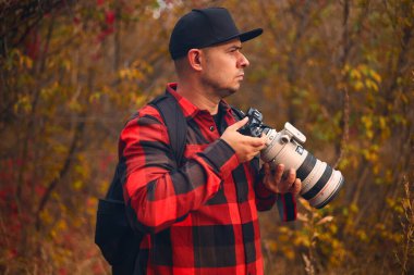 Sonbahar ormanında kameralı genç fotoğrafçı.