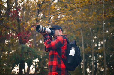 Parkta kamerası olan genç bir adam.