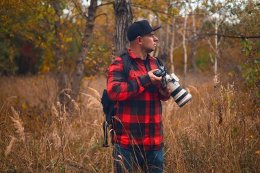 Sonbahar ormanında kameralı genç bir fotoğrafçı. Sonbahar kameralı bir adam. Sonbahar ormanında fotoğrafçı.