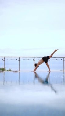 Güzel genç bir kadın sabah deniz sahilinde yoga yapıyor.