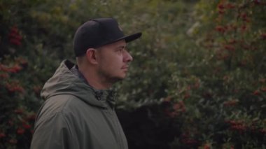 man in a hat and a backpack walking in the park