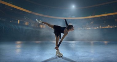 Artistik patenci kadın buz stadyumunda kayıyor..