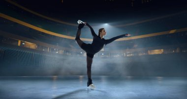 Artistik patenci kadın buz stadyumunda kayıyor..