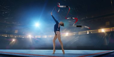 Geceleri profesyonel 3 boyutlu jimnastik stadyumundaki ritmik jimnastik kızı.