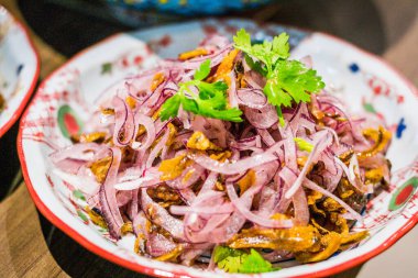 Porselen tabakta doğranmış kırmızı soğan ve lahana turşulu balık krakerleri.
