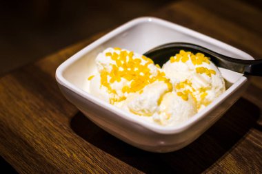 Üç kepçe hindistan cevizli dondurma bir kâsede ve bir fincan kahveyle servis edilir.