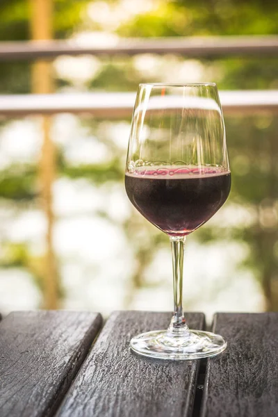 A wine glass of red wine on an outdoor al fresco dining table
