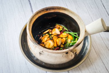 Kızarmış kurbağa bacağını taze soğanla karıştır ve kurutulmuş kamış biberi ile maydanozda servis et.