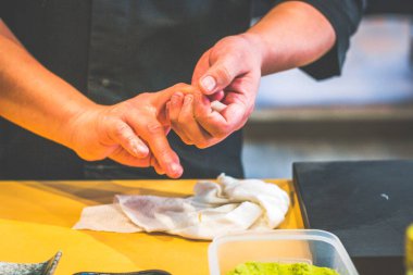 Japon restoranında şefin elleri Japon usulü suşi yapıyor.