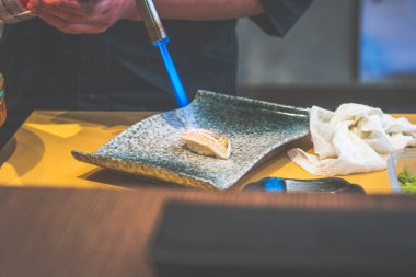 Japon restoranında şefin elleri Japon usulü suşi yapıyor.