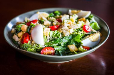 Sezar salatası, ızgara tavuk göğsü, kızarmış ekmek, haşlanmış yumurta ve vişneli domates.